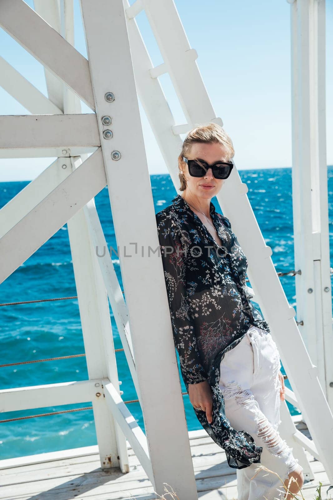 a woman by the sea near a wooden structure by Simakov