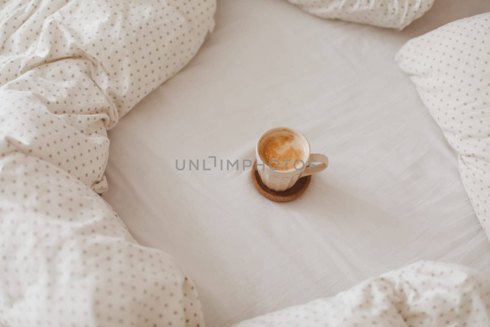 Cozy unmade bed with a coffee cup in the morning, breakfast in bed by paralisart