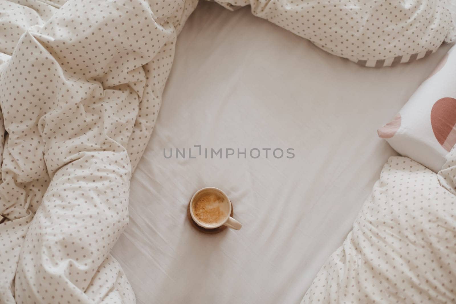 Cozy unmade messy bed with a coffee cup in the morning, breakfast in bed.