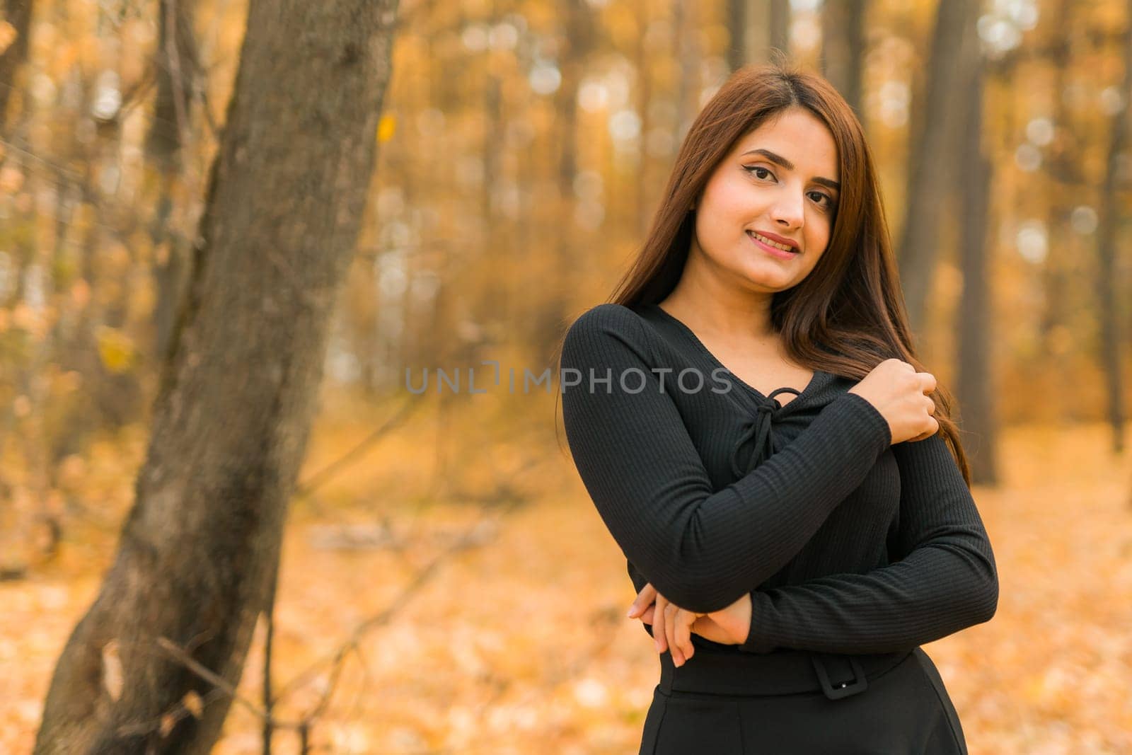 Close-up portrait of a young beautiful confident Indian Asian woman in fall outdoor. Happy and natural smiling female. Generation z and gen z youth