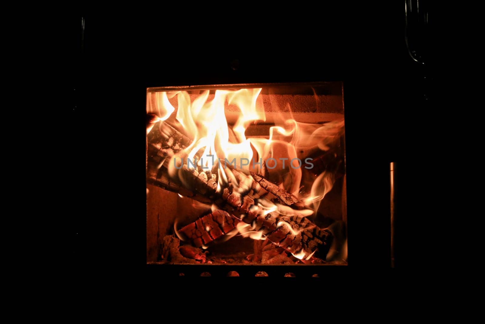 Bright colored dancing flames in fireplace. Close up of burning firewood. Cozy warm background.
