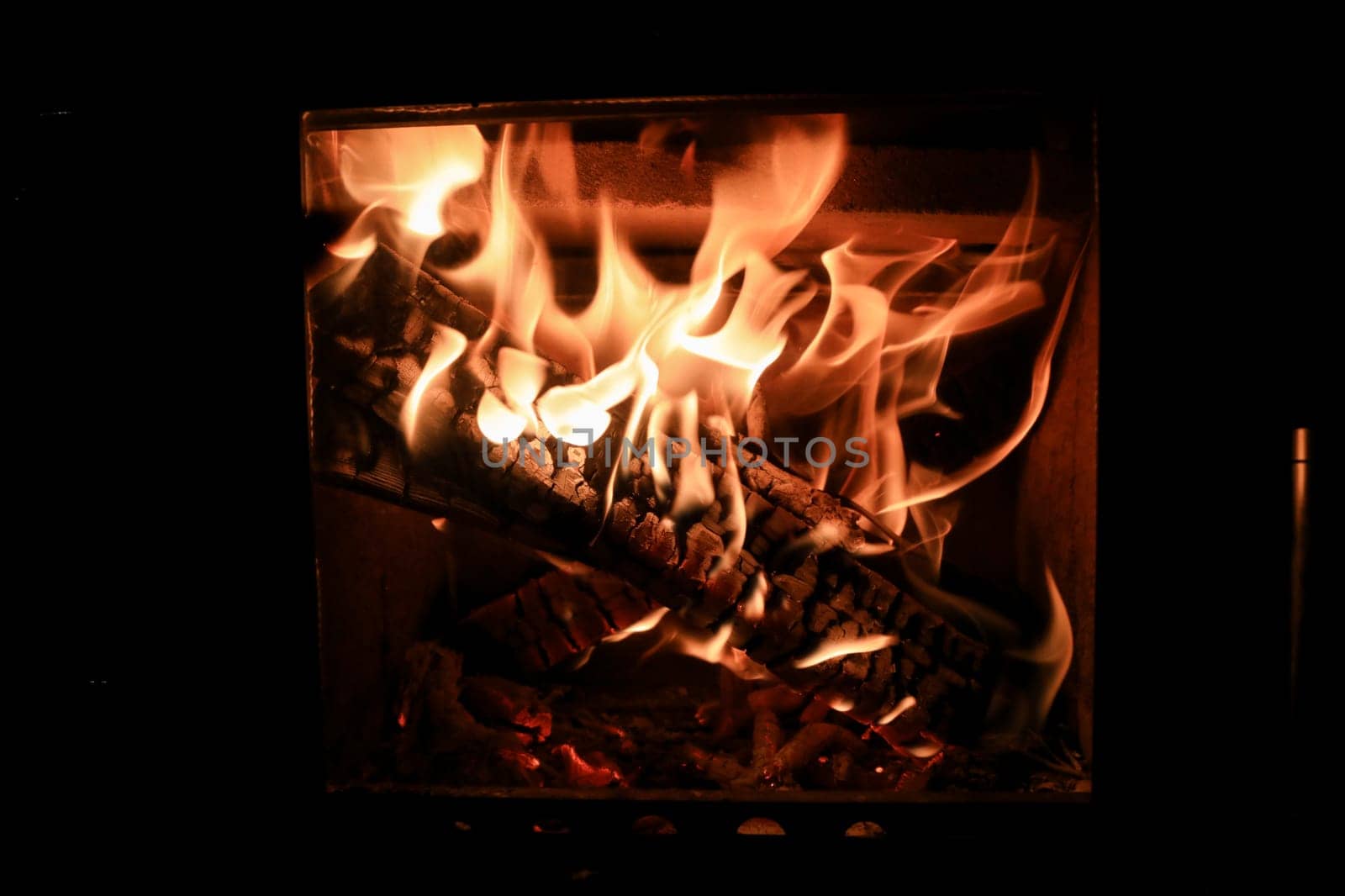 Bright colored dancing flames in fireplace. Close up of burning firewood. Cozy warm background.
