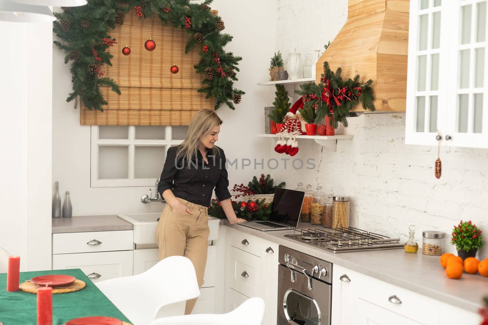 charming woman laptop while having breakfast in cozy kitchen Christmas time