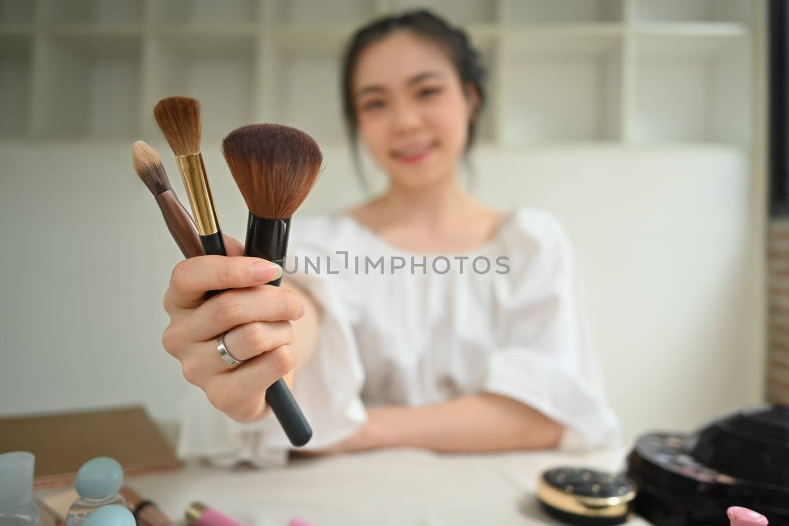 Cheerful female makeup artist holding set of make up brushes and smiling by prathanchorruangsak