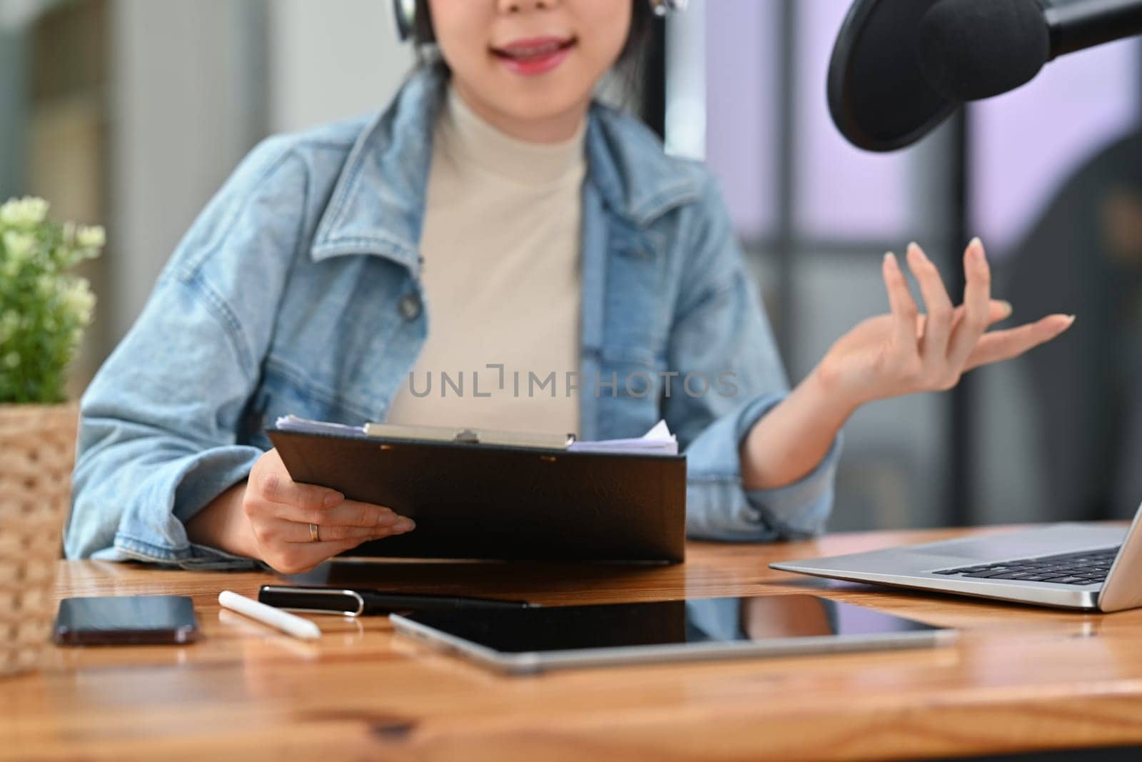 Female radio host discussing various topics with her guest while streaming live audio podcast from home studio.