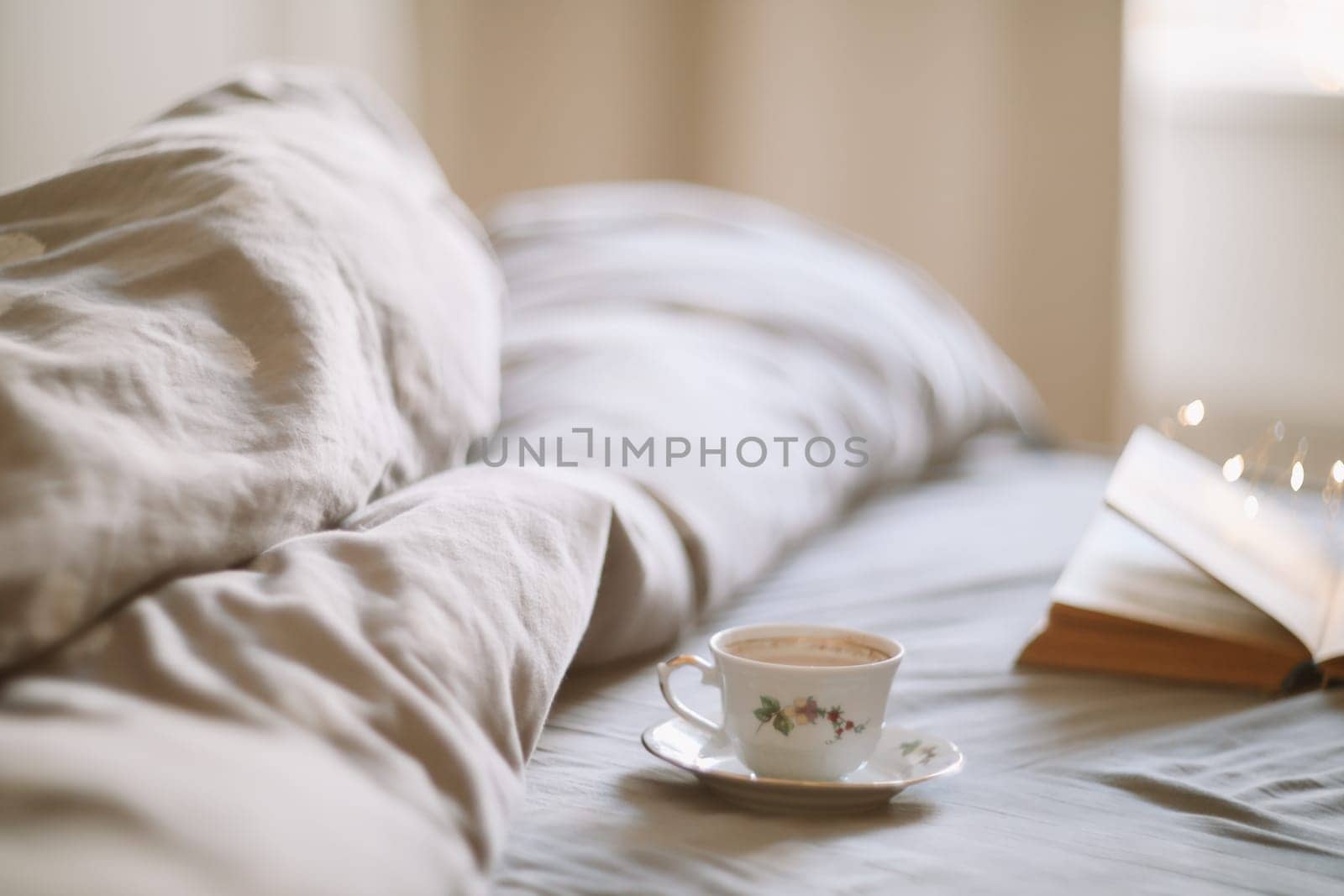 Light cozy bedroom, Coffee or tea cup and an open book on the bed. Spring still life. Breakfast in bed. by paralisart
