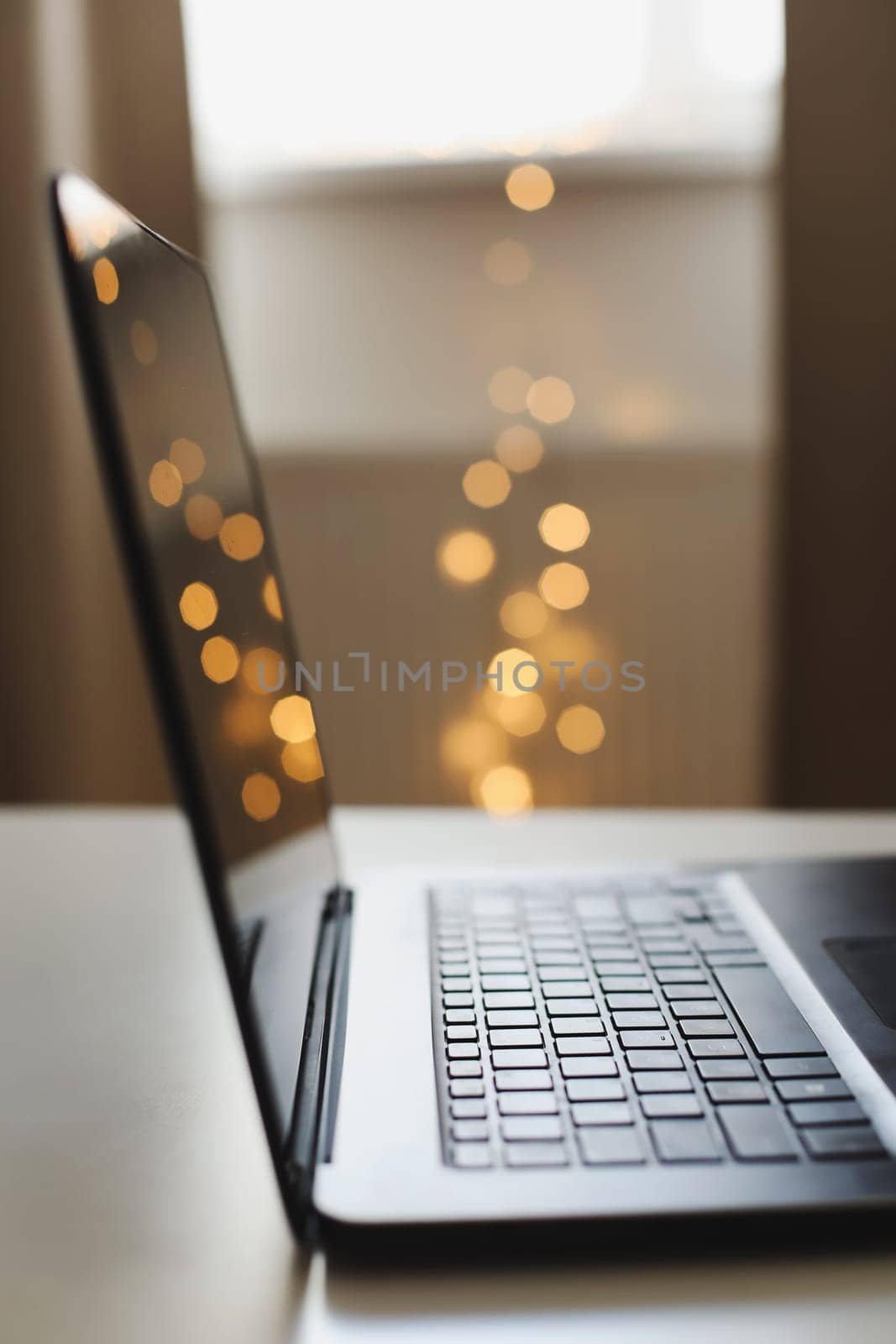 Close up of laptop keyboard with blank screen on a table by blurry bokeh lights background in the house or office modern, sunlight in morning by paralisart