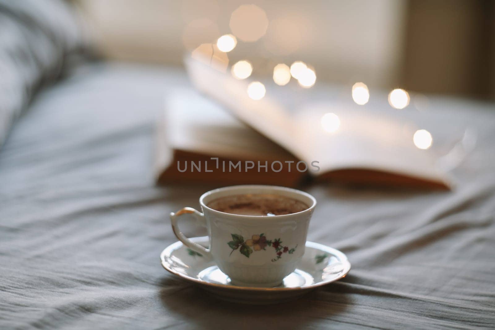 Light cozy bedroom, Coffee or tea cup and an open book on the bed. Spring still life. Breakfast in bed. by paralisart