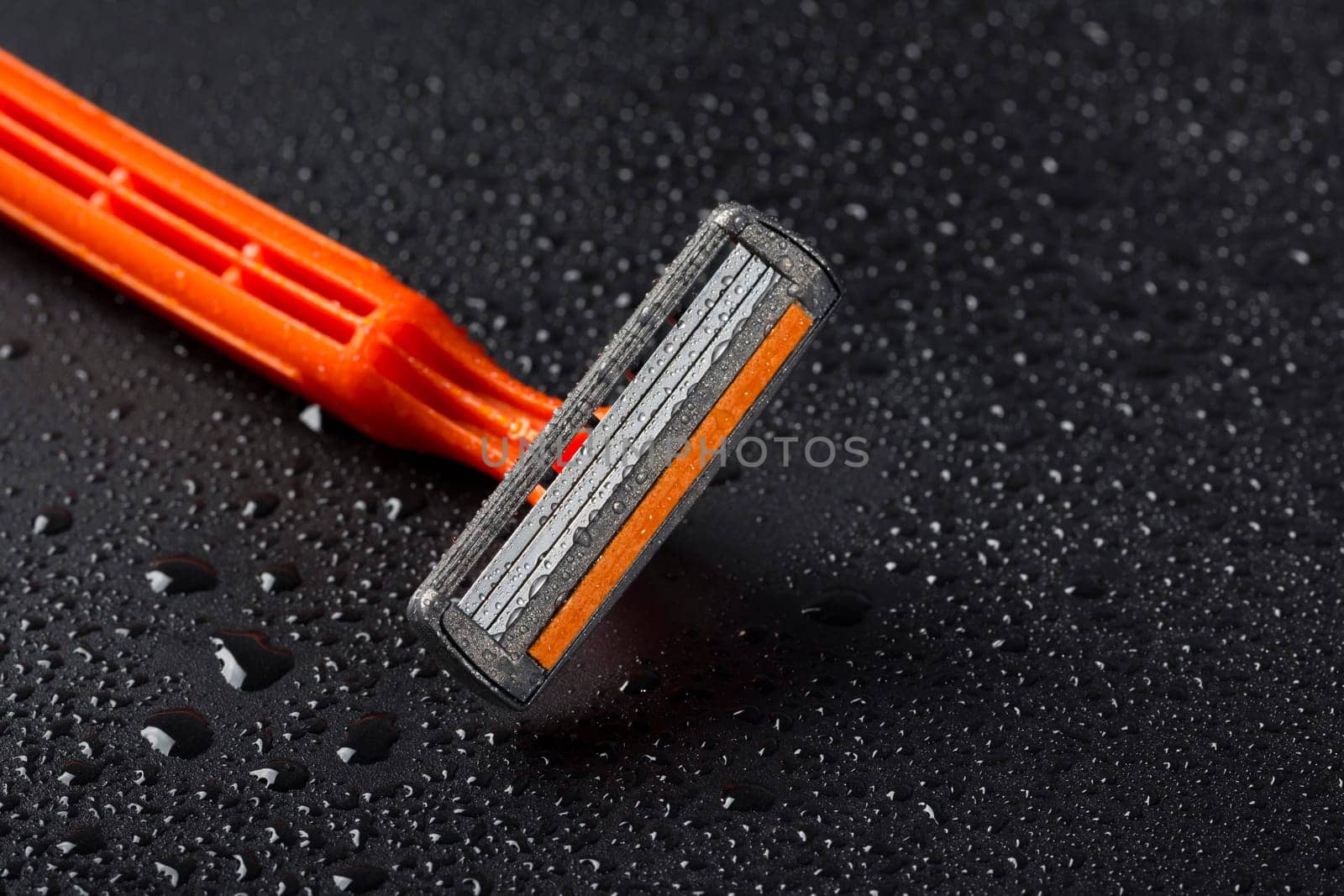 Razor with drops of water on a black background. Close-up. New razor blade. Skin care concept by Shablovskyistock