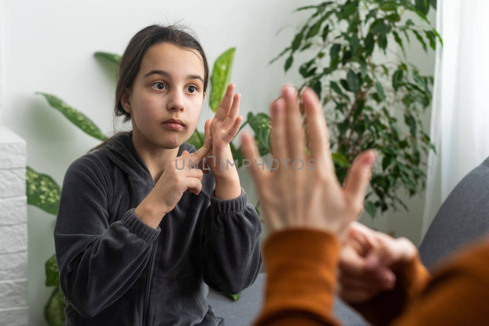 Cute little girl make hand gesture learning sign language with mom or female nanny, smiling small kid practice nonverbal talk with teacher at home, preschooler disabled child have lesson with tutor.