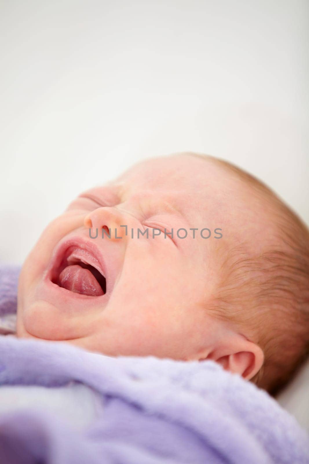 Sad, crying or tantrum with a baby on a bed closeup in a home for emotion, expression or child development. Face, tired or hungry with a newborn infant in the bedroom of an apartment for growth by YuriArcurs