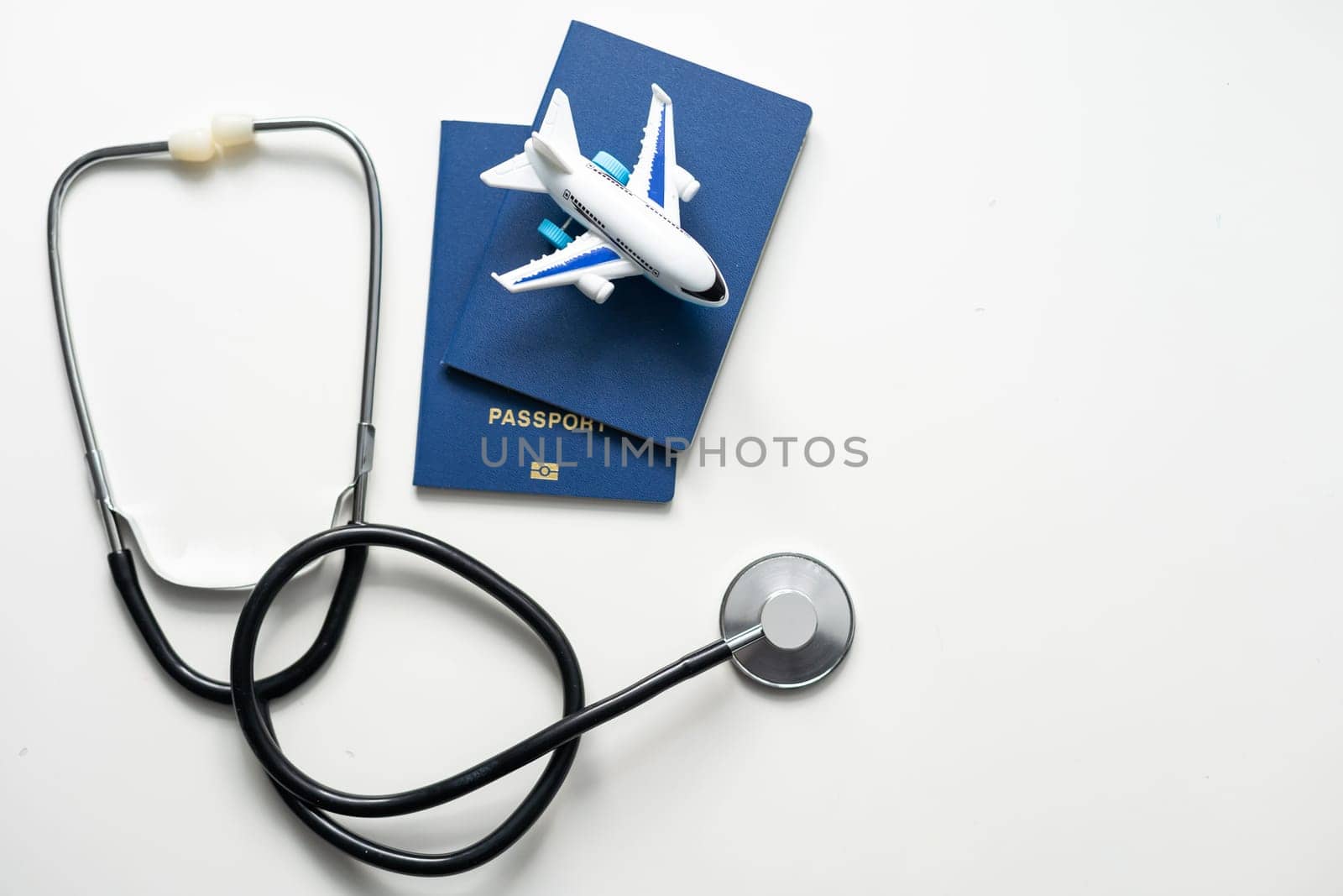 Medical Tourism, medical travel concept. Stethoscope, toy plane and passport on grey background