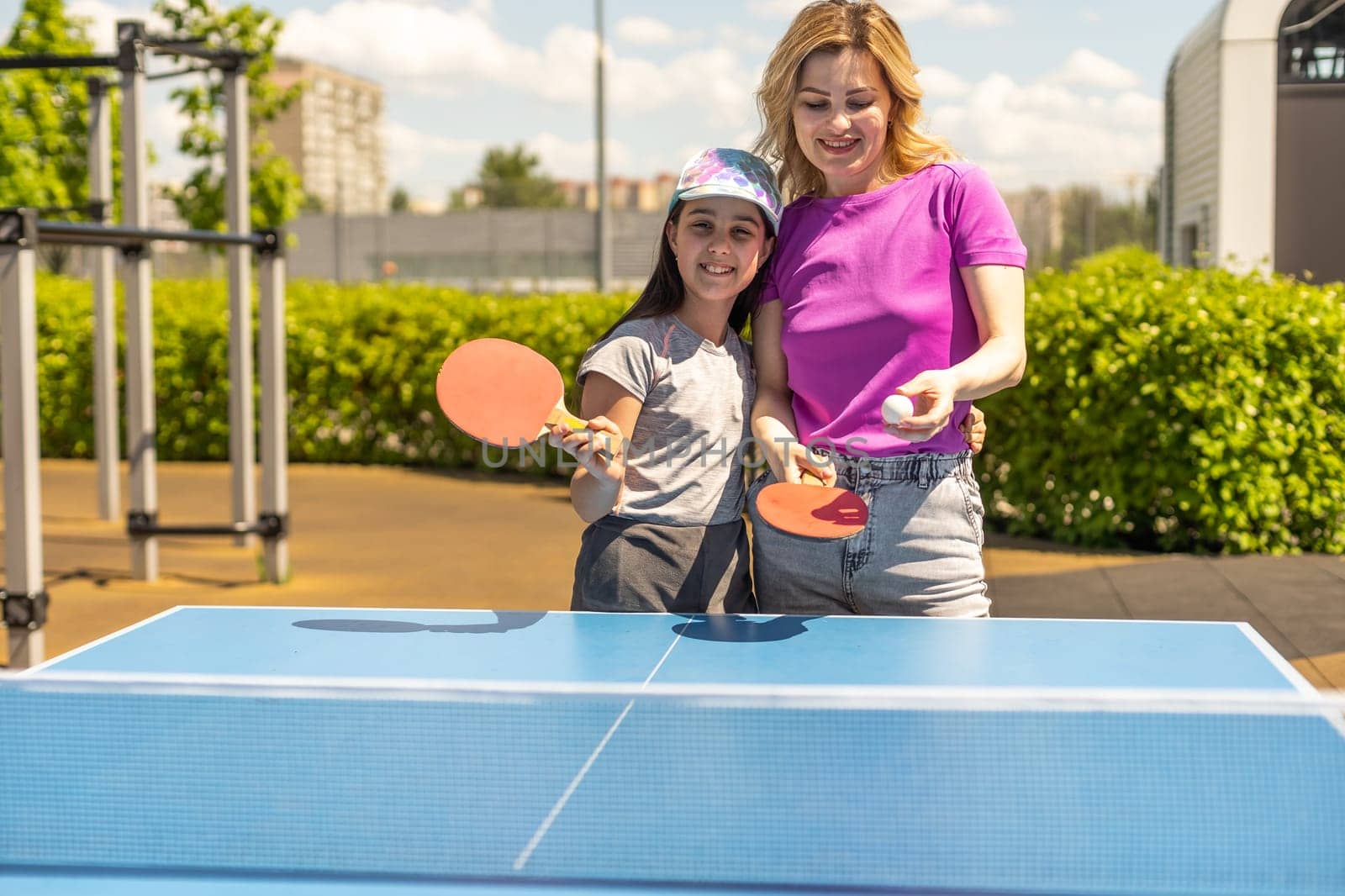 Young woman with her daughter playing ping pong in park.