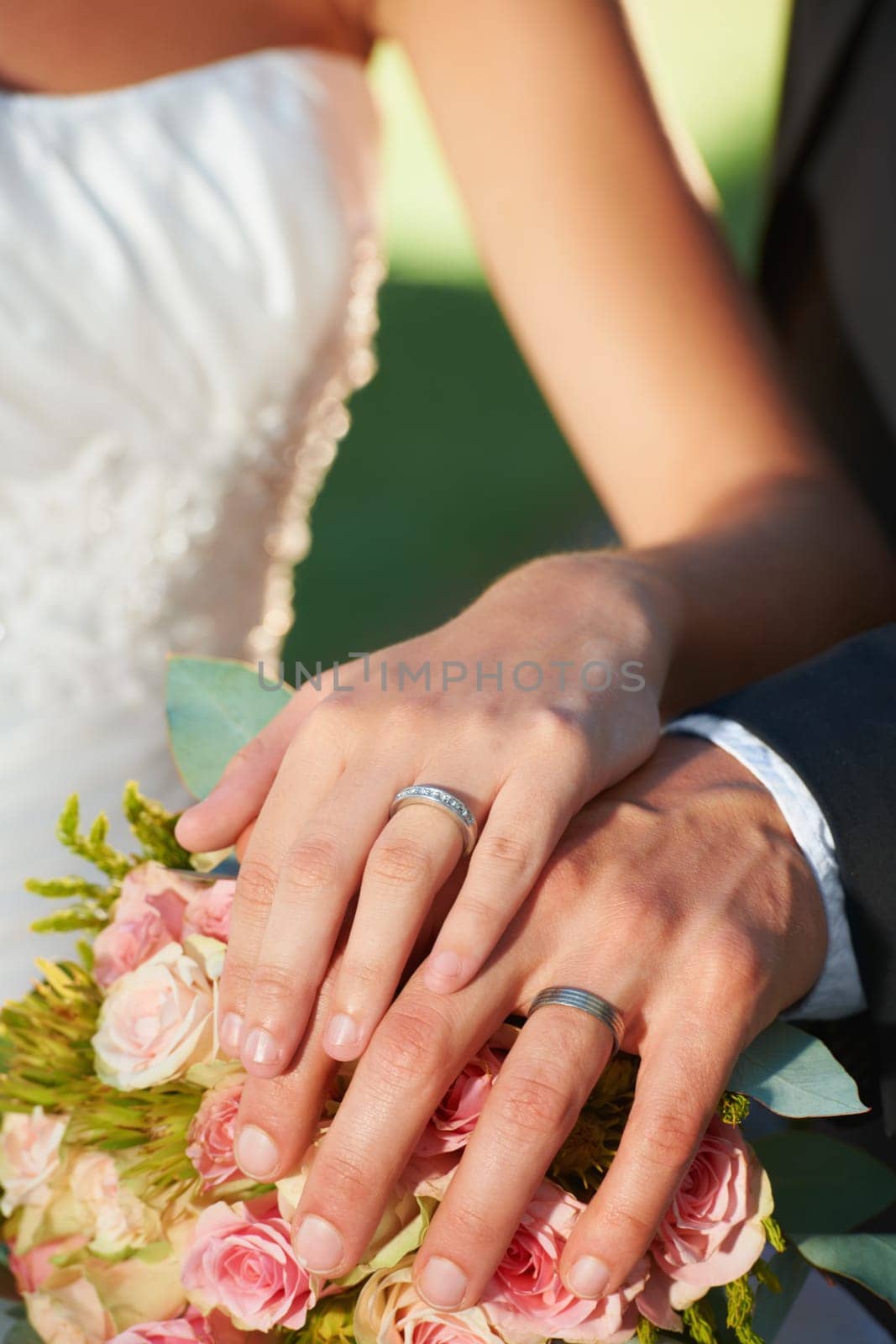 Couple, wedding ring and hands in marriage with rose bouquet at celebration and trust event. Flower, loyalty and care with romance and groom jewelry with love and commitment with woman and man.