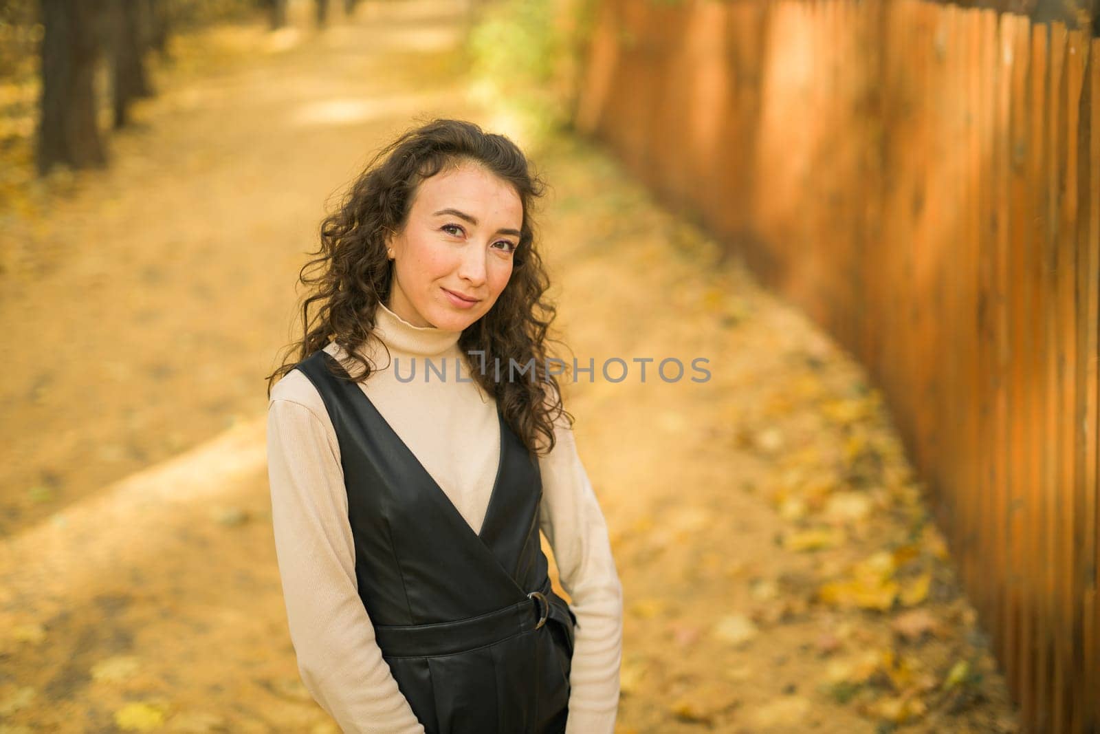 Autumn portrait of a beautiful happy curly woman in fall season. Millennial generation female. Natural beauty