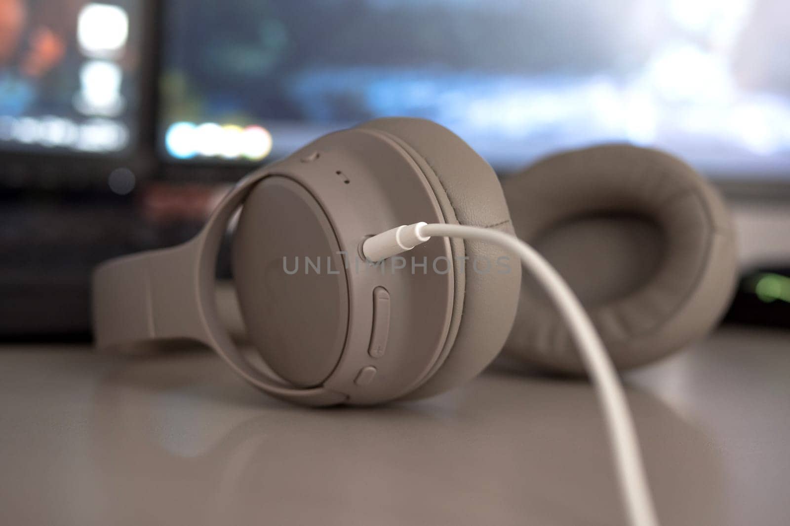 wired headphones close up on a desk with monitors on background.