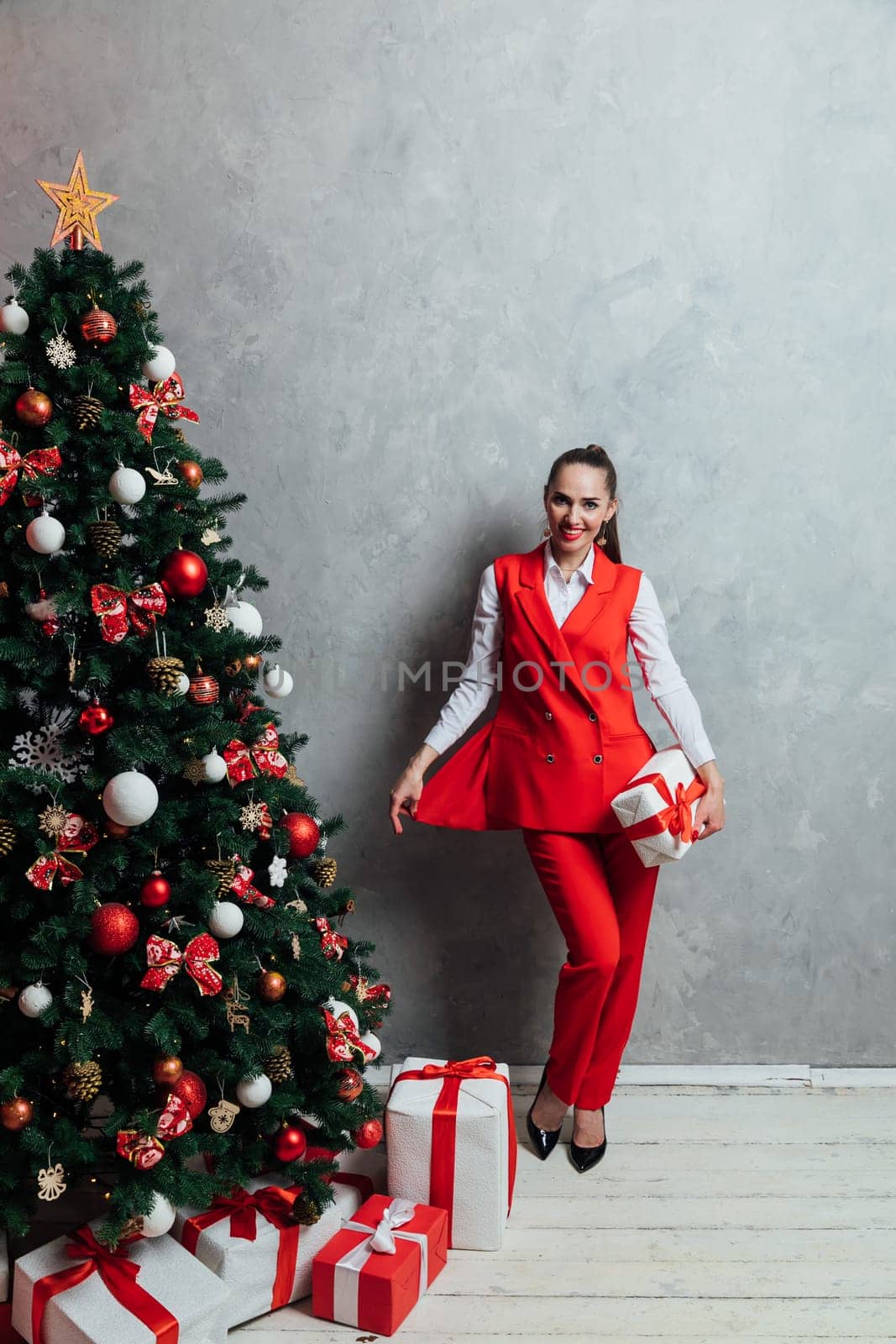 Woman decorating christmas tree with gifts for new year by Simakov