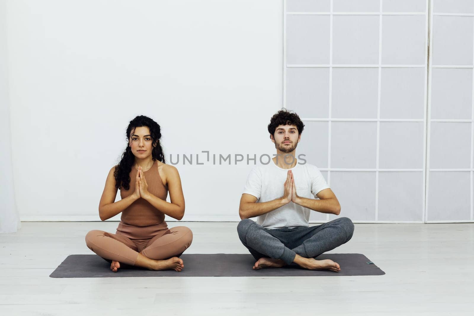 Yoga group concept. Young couple meditating together, sitting back to back by Simakov