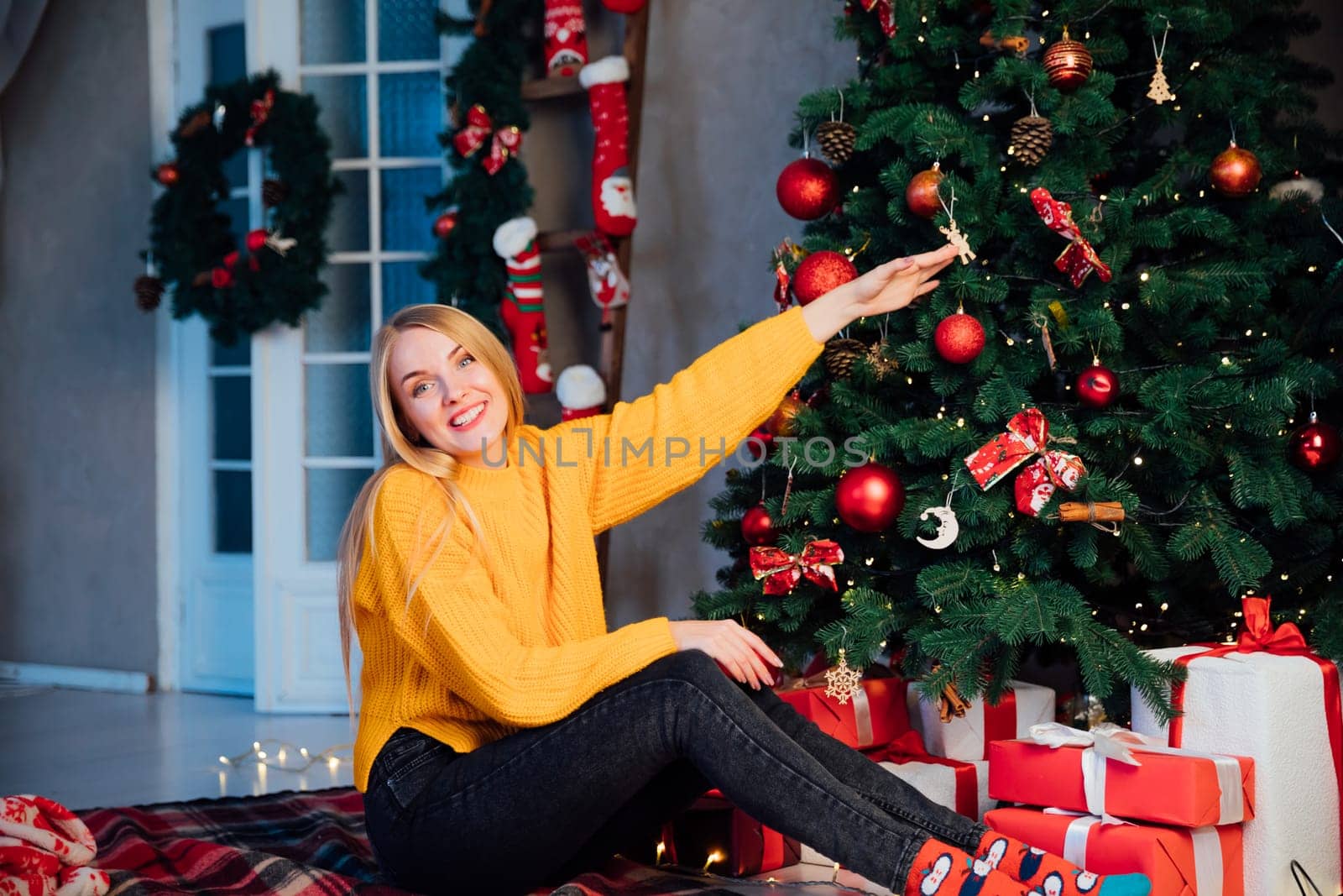 Blonde woman at christmas tree with gifts for new year by Simakov