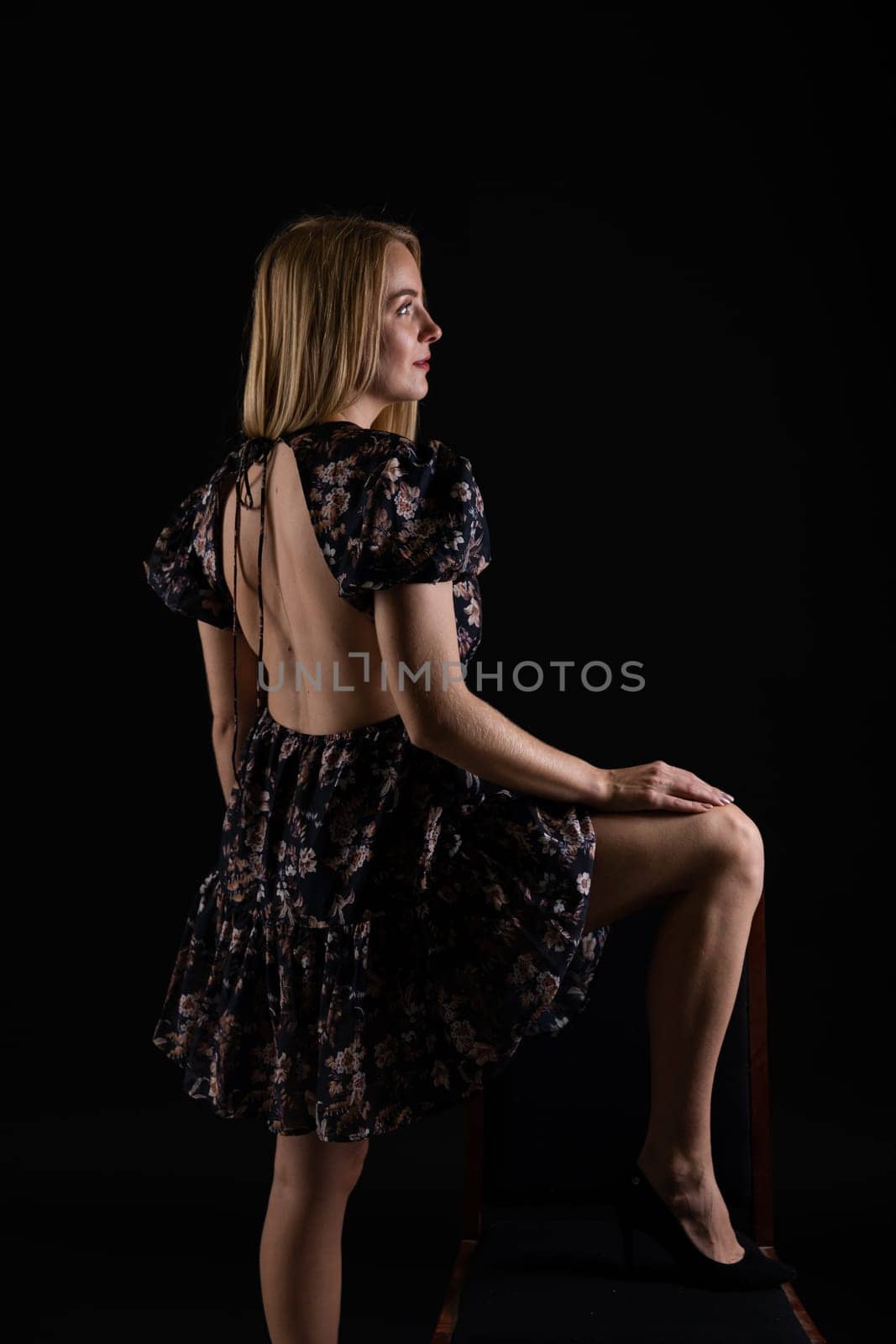 Portrait of a slender blonde woman in a dark summer dress