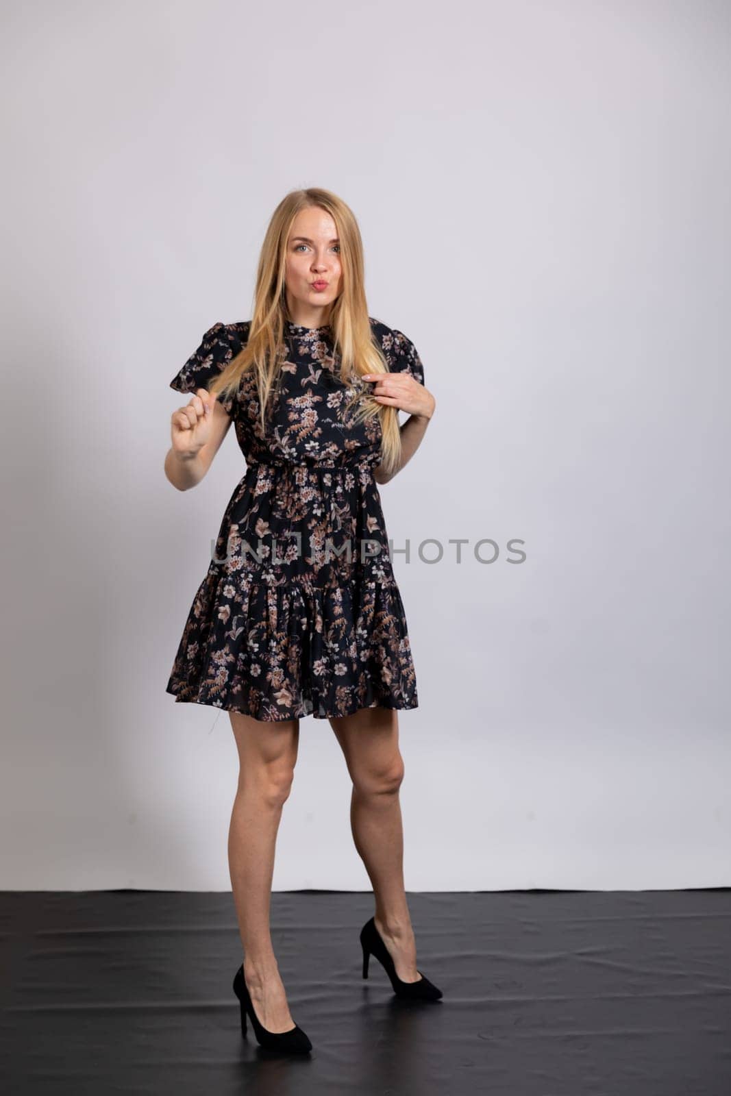 Portrait of a slender blonde woman in a dark summer dress