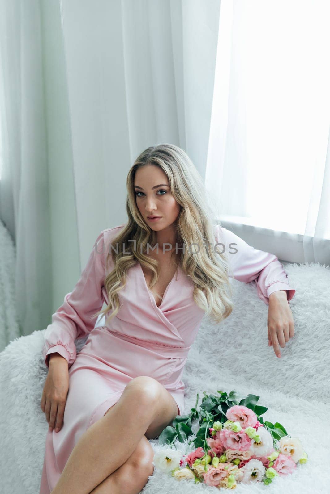 Portrait of a delicate woman in a pink dress with a bouquet of flowers