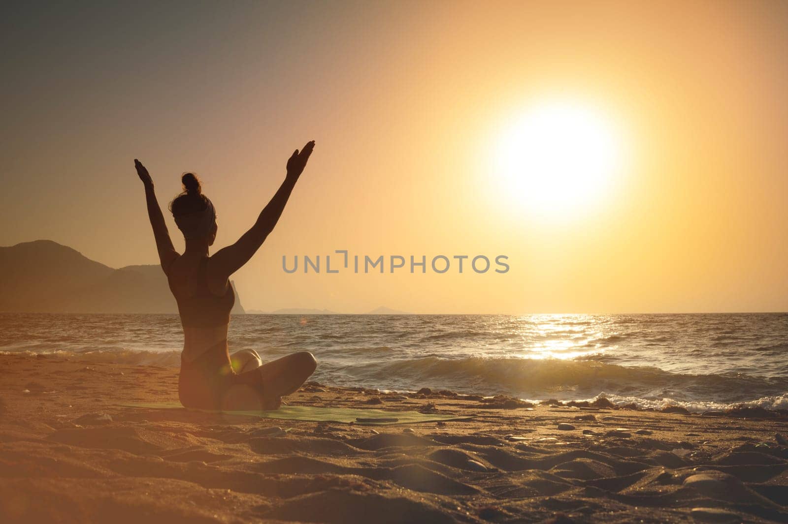 gorgeous woman practicing yoga, raising her arms, feeling so good and happy, young woman seeking enlightenment through meditation on the sea.
