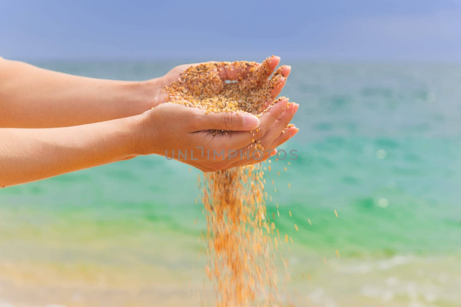 Young woman with sand in her hands. Yellow sand crumbles into and through a woman's hands by yanik88