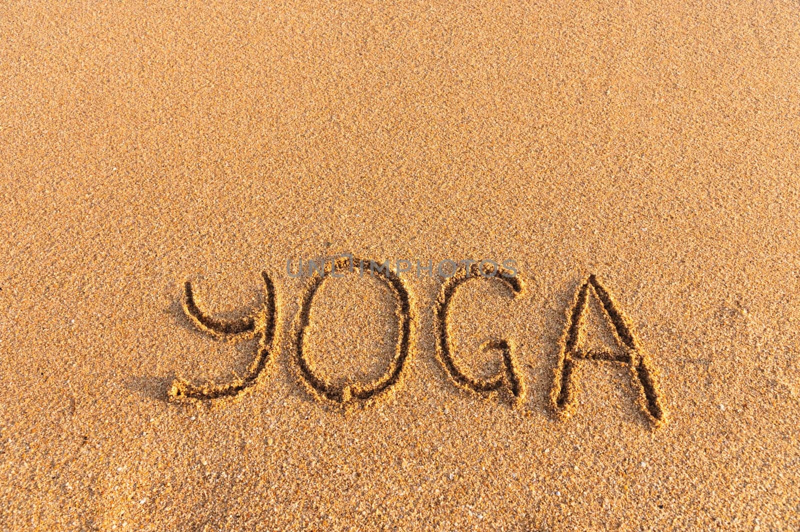 The inscription yoga on the sea sand. sea coast with yoga post with place for text.