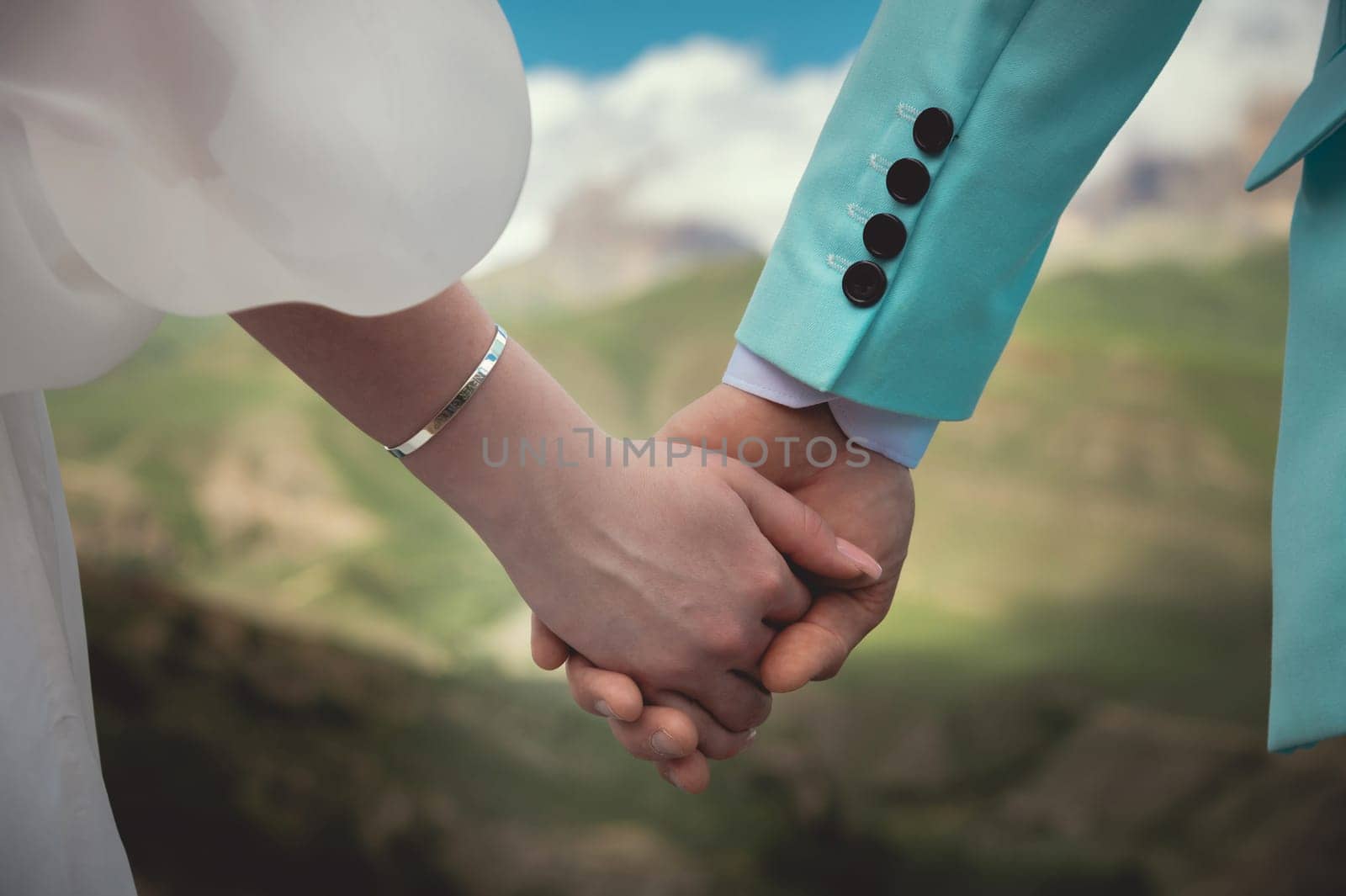 Touching hands of a man and a woman, close-up. Strong tender embrace of two lovers against the backdrop of the mountains. The hands of a young couple hold each other. Feeling of love.