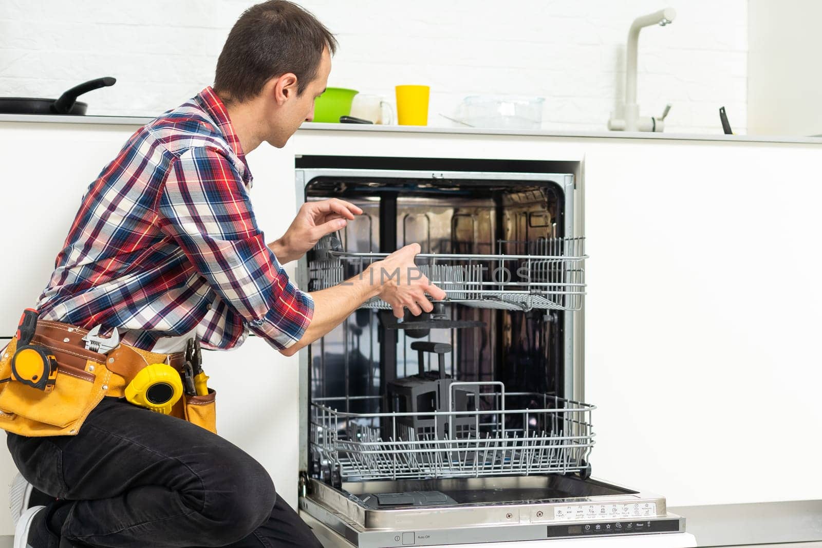 Man repairing a dishwasher with tools by Andelov13
