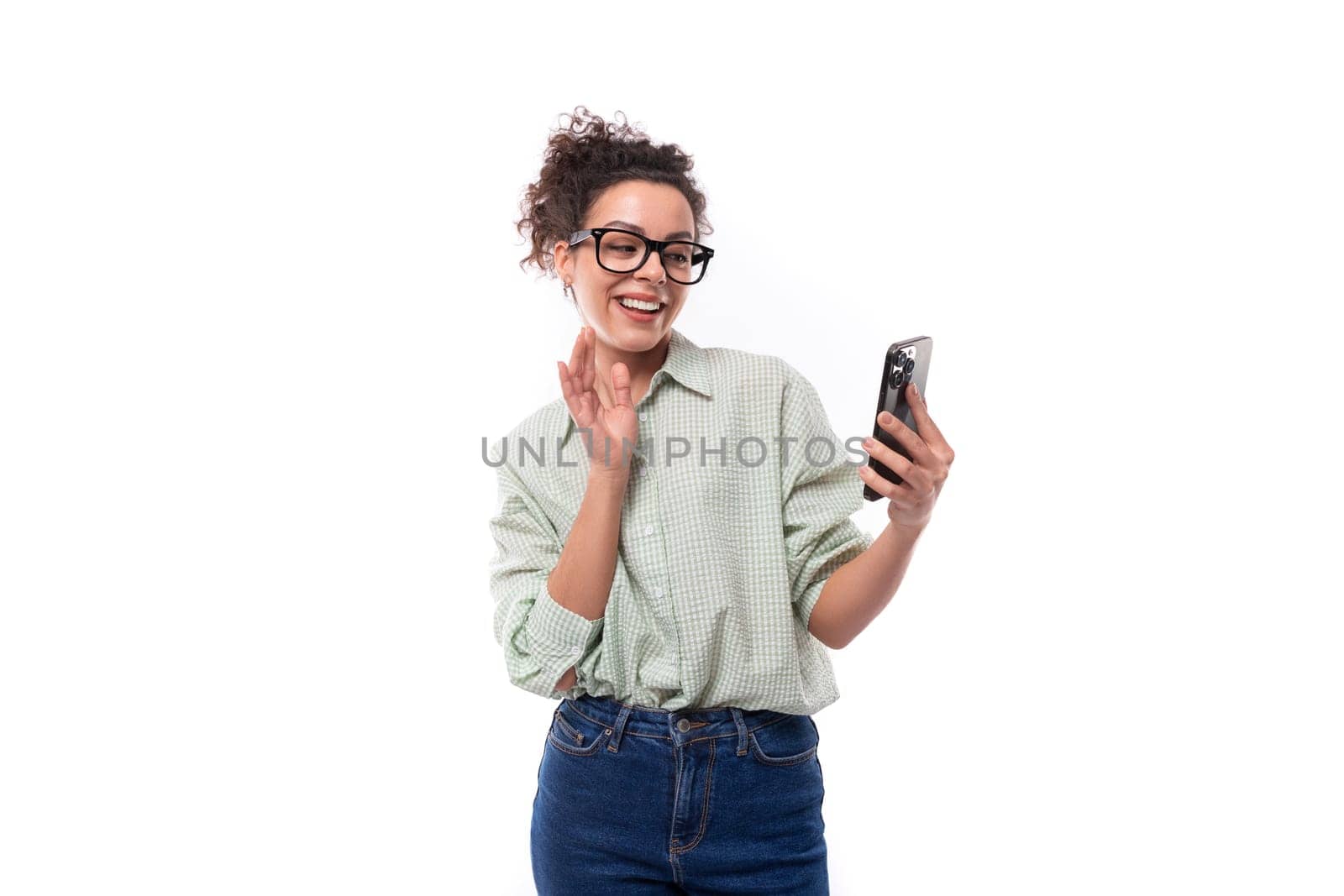 young smiling woman student with curly hair in a shirt communicates via video call on the phone.