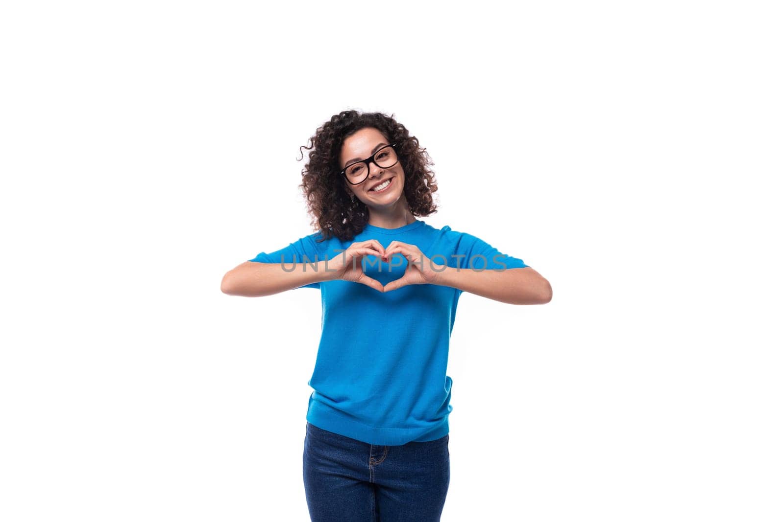 friendly young curly brunette woman in blue t-shirt showing heart.