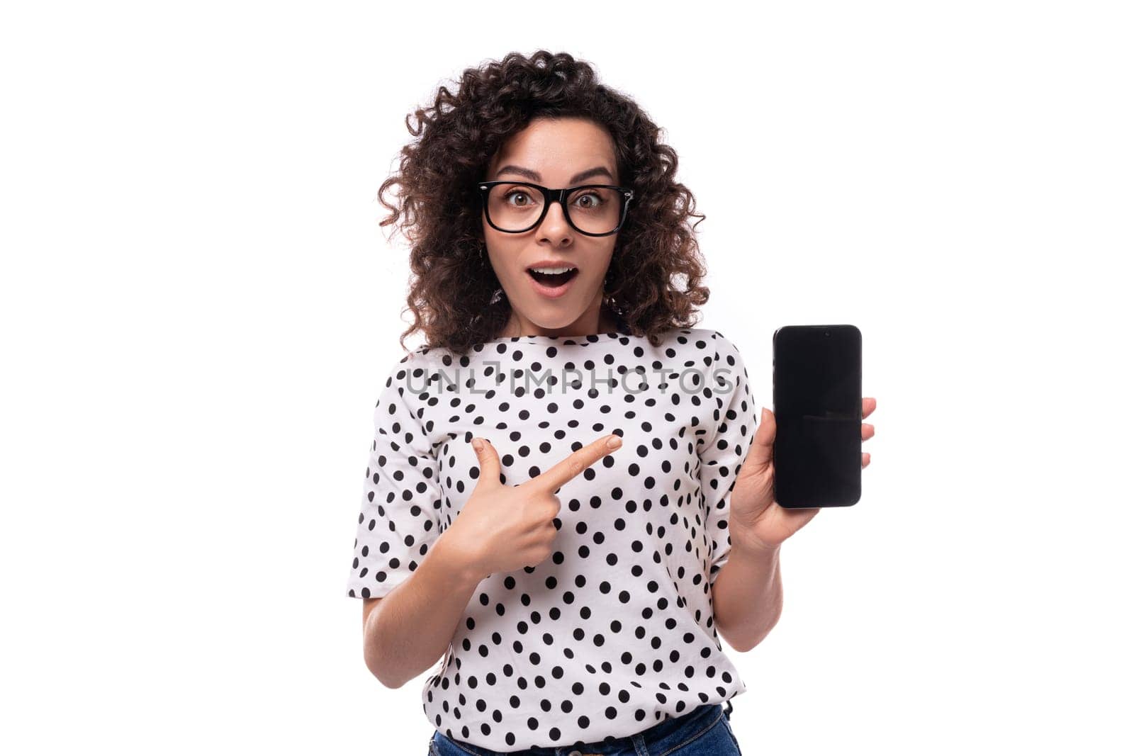 young stylish caucasian woman with curly perm hair shows phone with mockup by TRMK