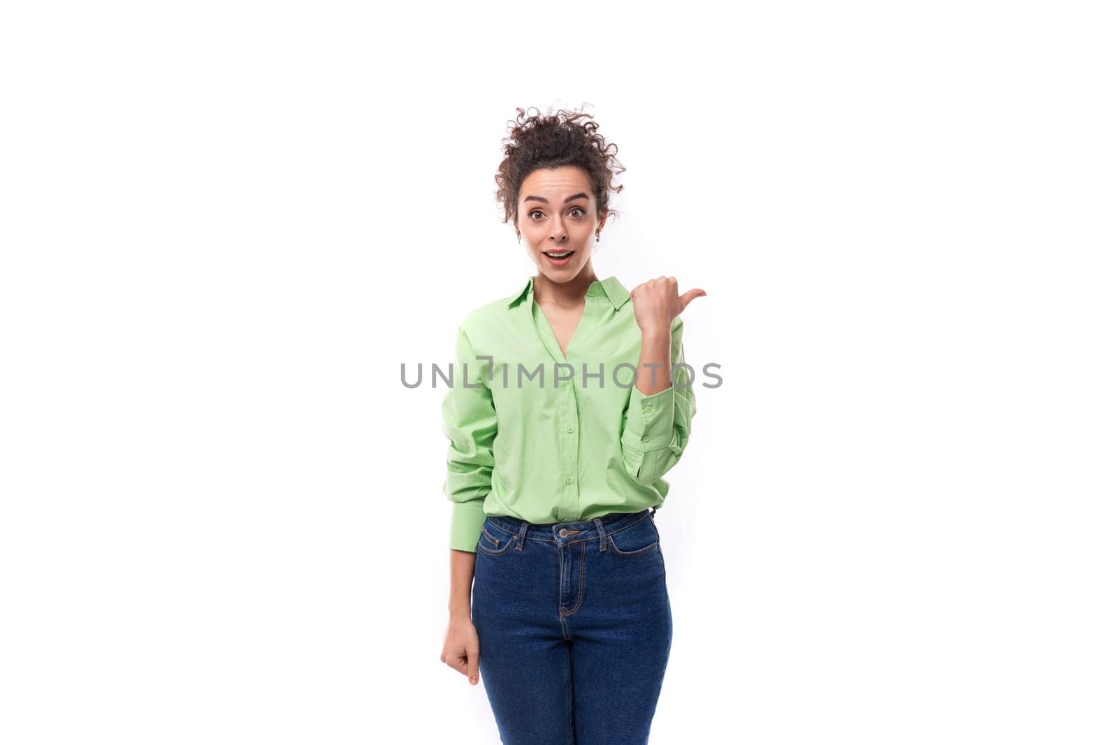 young well-groomed slender European brunette curly woman dressed in a green shirt on a white background.