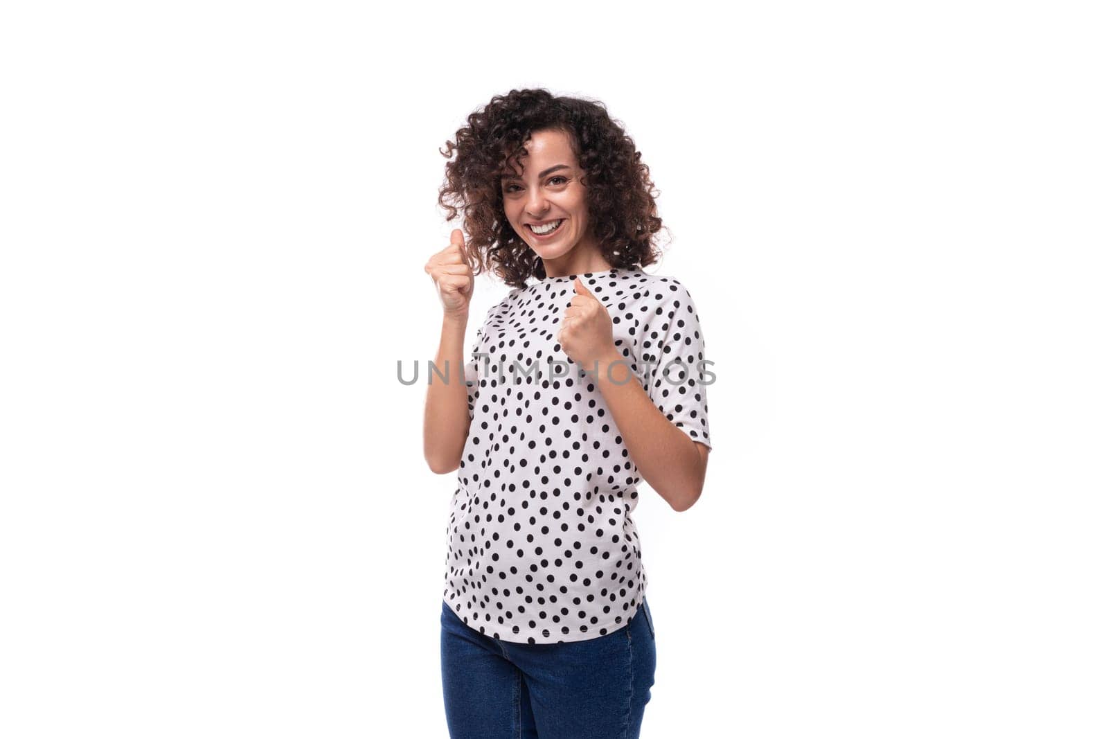 portrait of a pretty curly young brunette woman with shoulder length hair dressed in a short sleeved shirt.