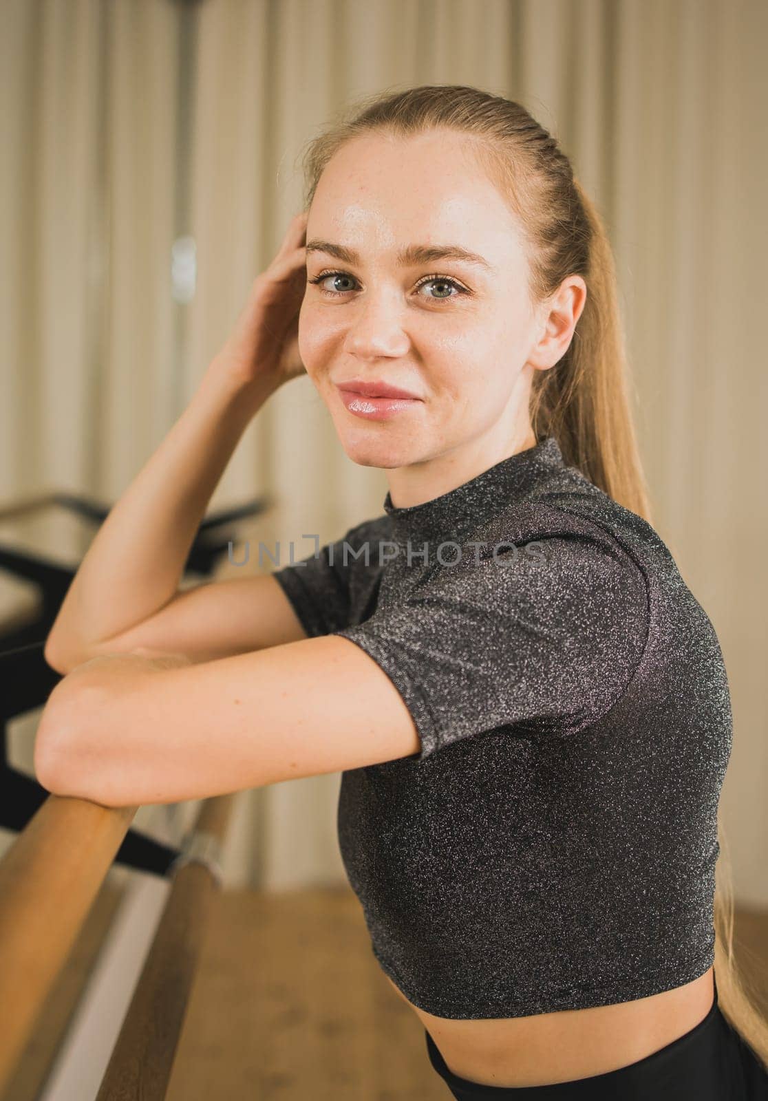 Female ballet dancer resting at barre and mirror in dance studio - dance and ballerina