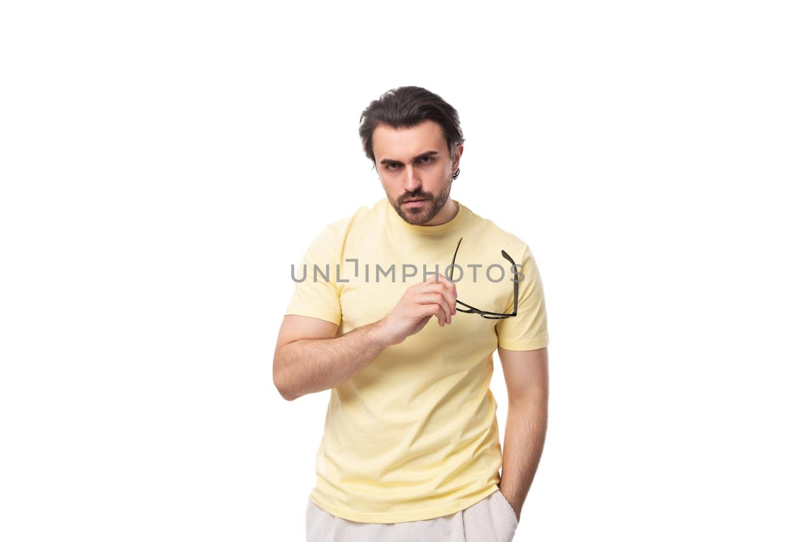 handsome young brunette man with a beard put on glasses for vision correction.