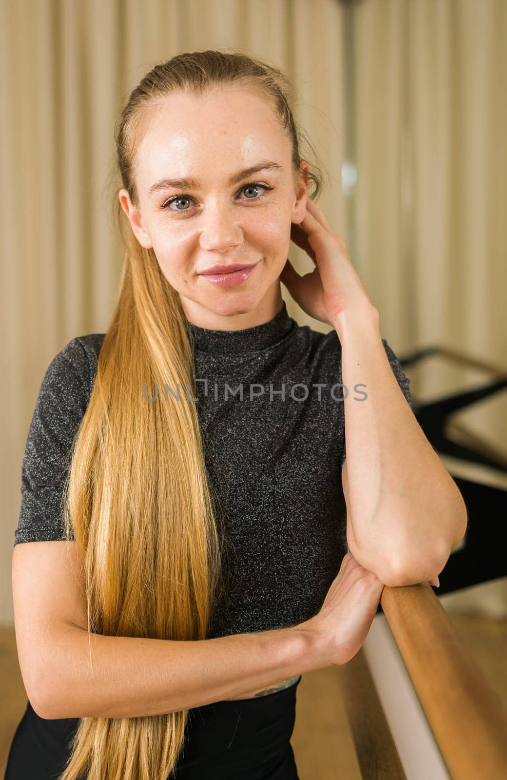 Female ballet dancer resting at barre and mirror in dance studio - dance and ballerina