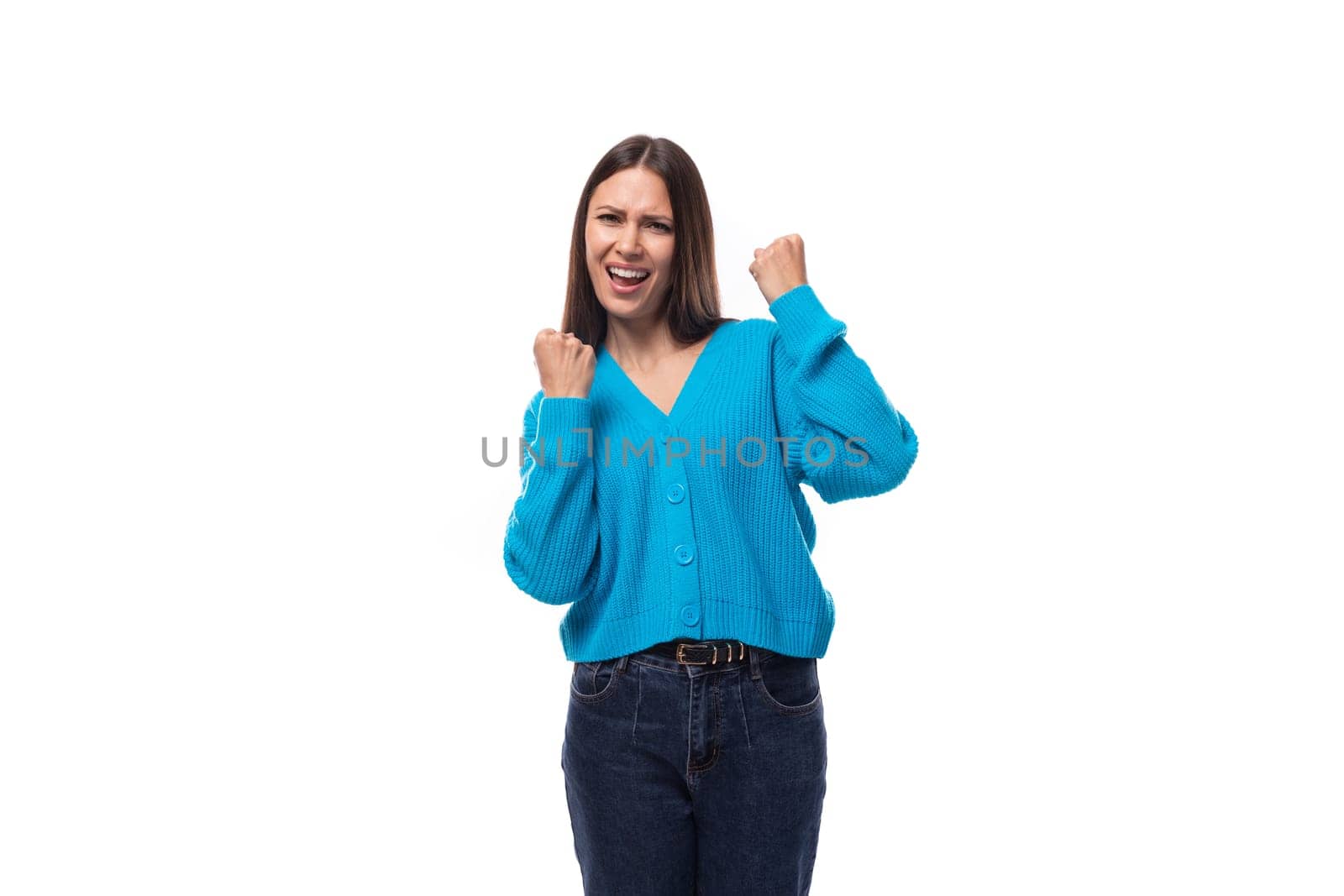 young pretty caucasian woman with black hair dressed in a stylish blue cardigan rejoices.