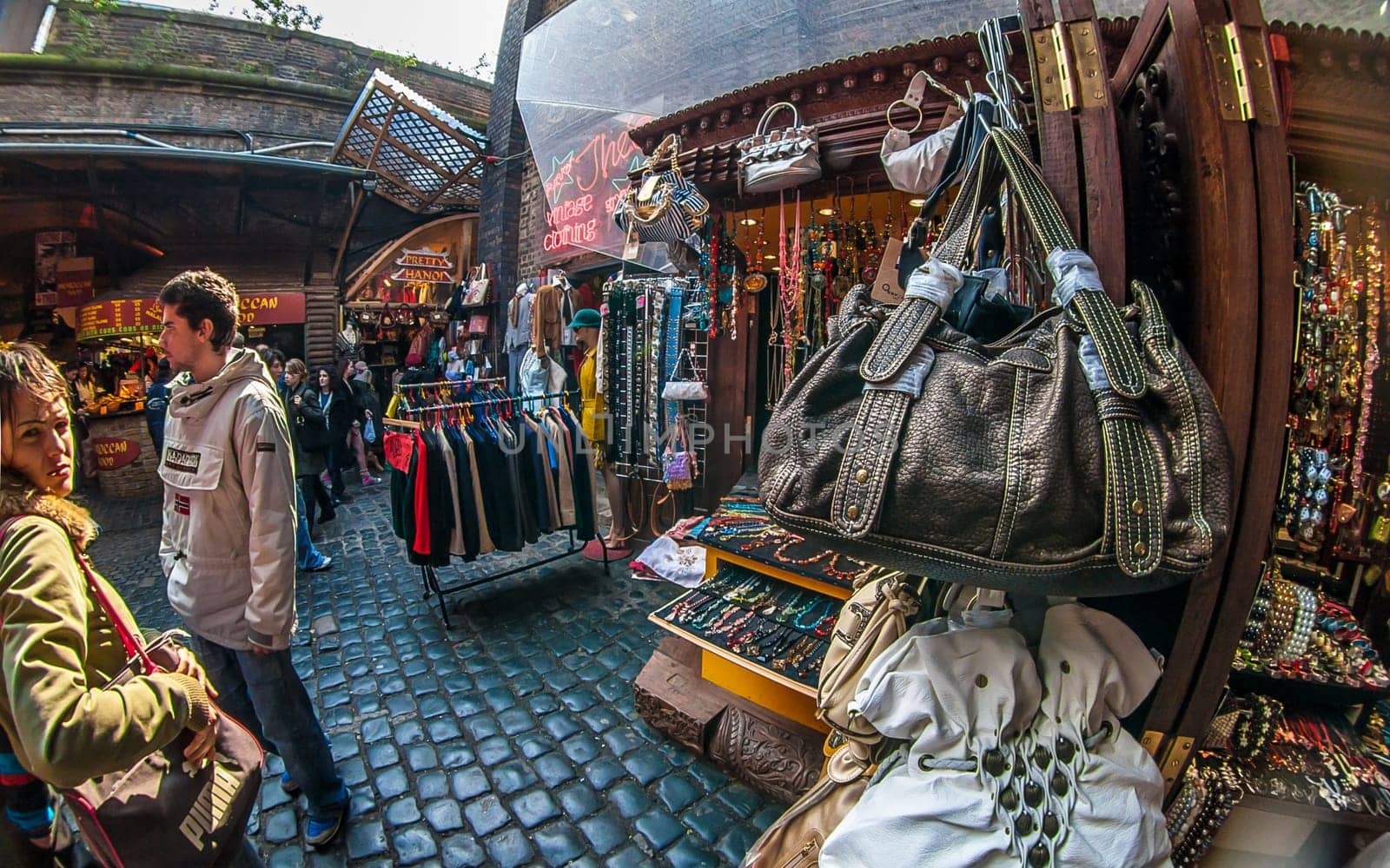 London, United Kingdom - March 31, 2007: Extreme wide angle (fisheye) photo of bags, clothes and other accessories on display at Camden Lock, famous flea market in UK capital. by Ivanko