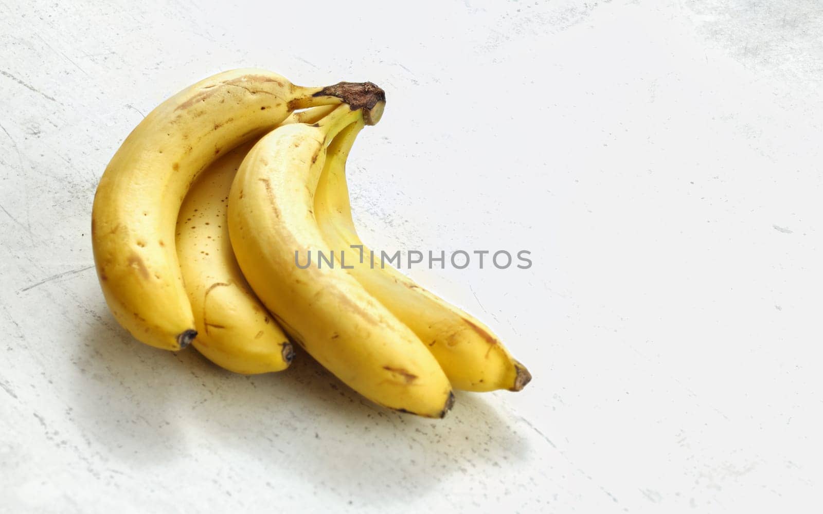 Bunch of ripe bananas on white working board.