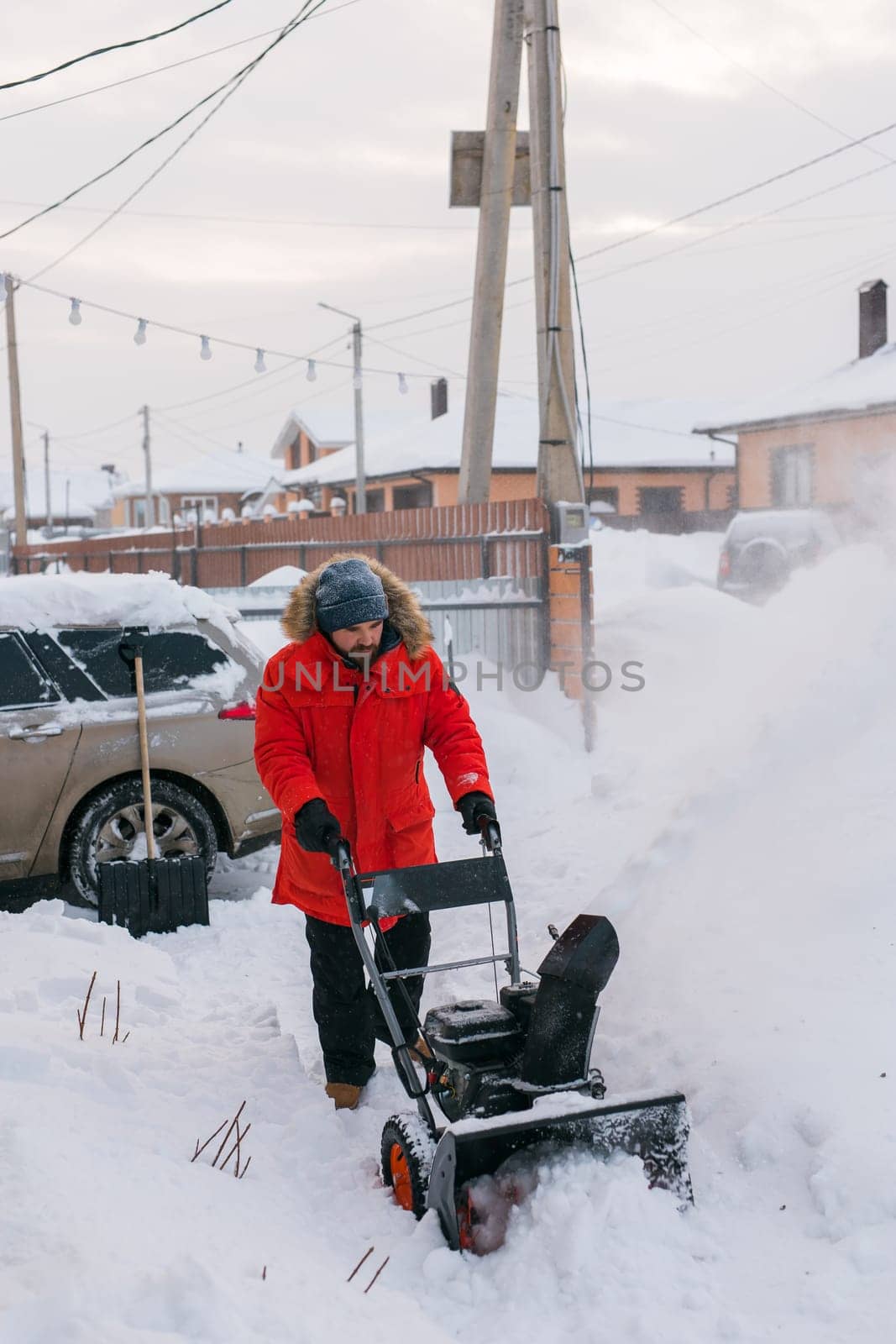 A man clear snow from backyard with snow blower. Winter season and snow blower equipment.