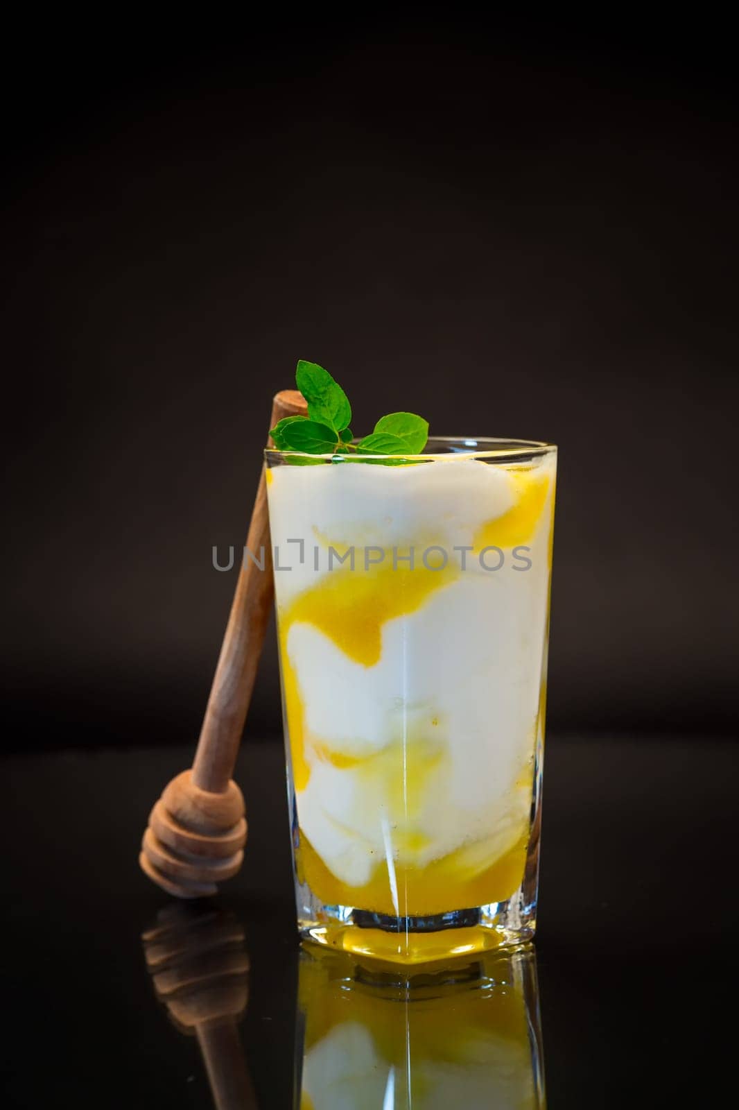 prepared homemade yogurt with natural honey in a glass isolated on a black background.