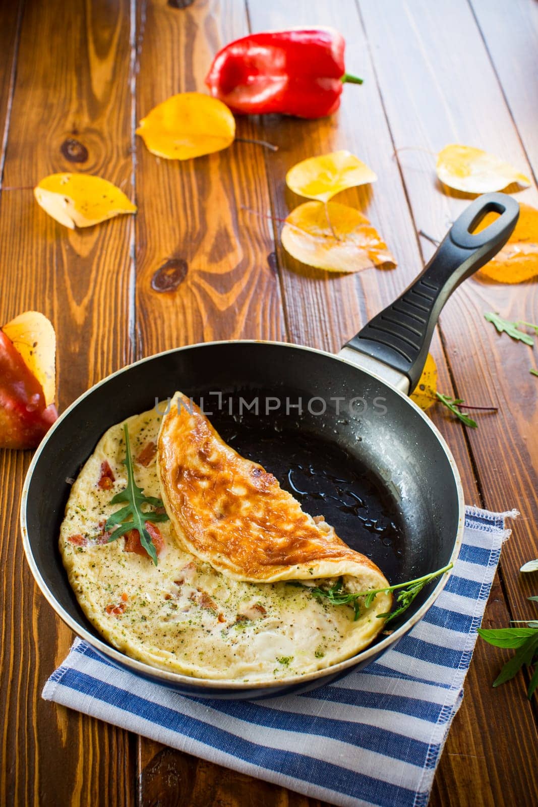 Fried omelets with various autumn vegetables in a frying pan on a wooden table. Autumn recipes.
