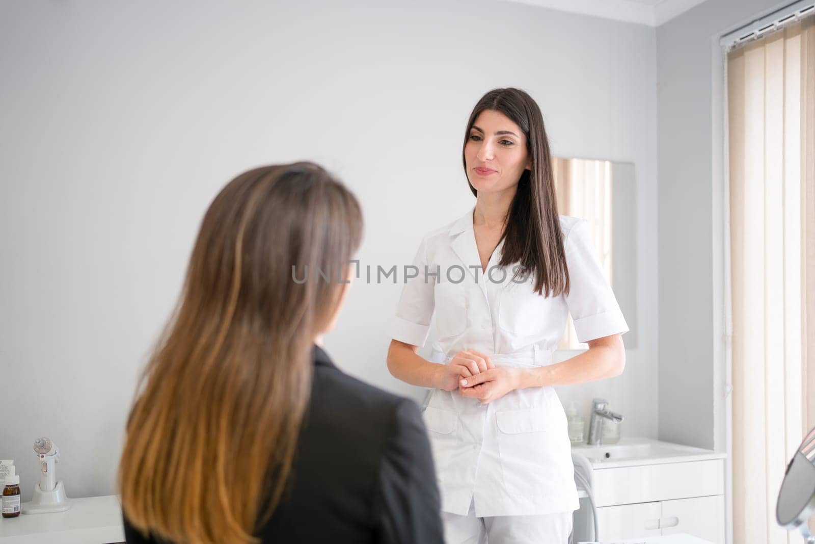 Female professional beauty doctor talking with young female. Beauty therapist talks to client about facials procedure. Dermatologist and patient in clinic