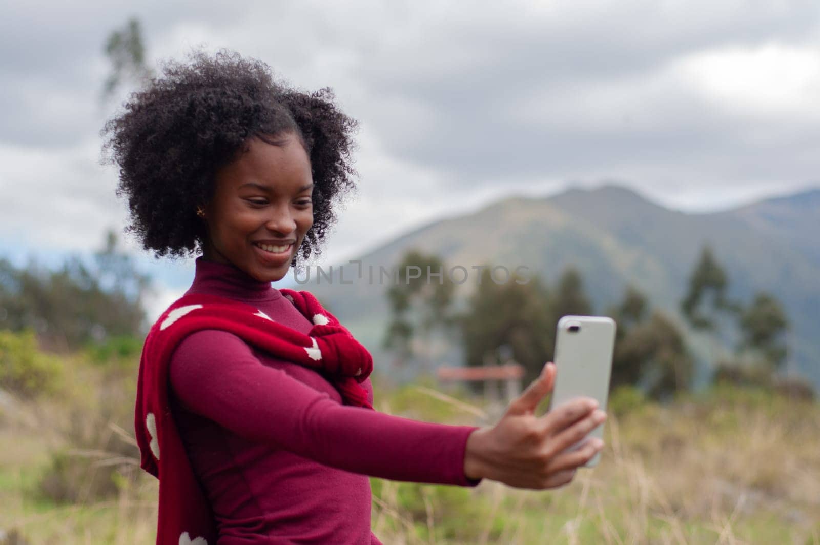 afro girl connected in a live broadcast with her followers outdoors with a beautiful smile by Raulmartin