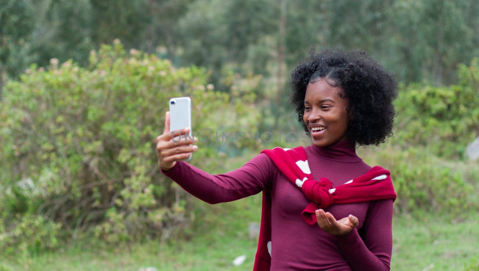 Afro girl talking to her social media followers in a live mountain live on a mountain dressed in red. High quality photo