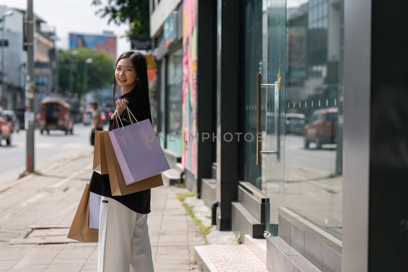 Young asian woman in shopping. Fashion woman in black with shopping bag walking around the city after shopping. Black friday by itchaznong