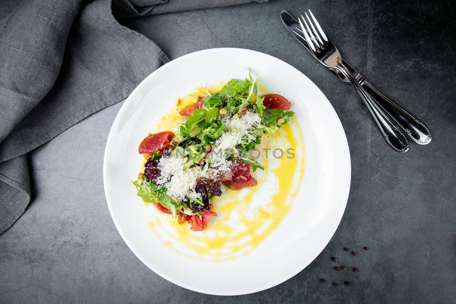 side view of salad with red fish, herbs and cheese on a white plate by tewolf